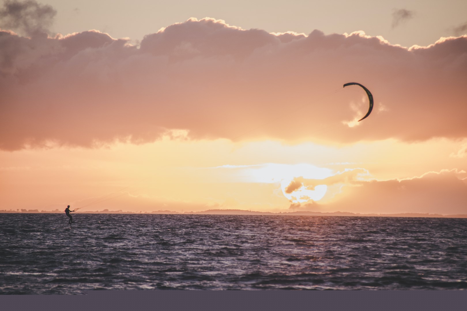 A person kitesurfing at sunset